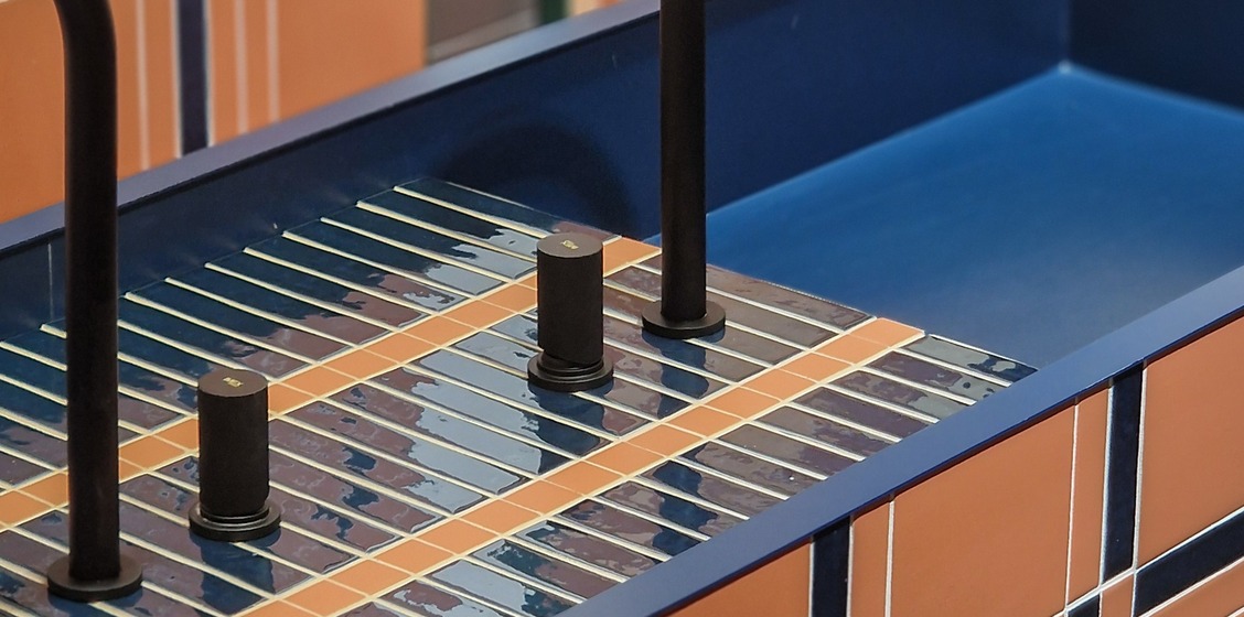 Blue and terracotta ceramic composition around a washbasin at the WOW Design Cersaie stand